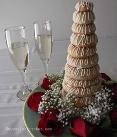 a plate topped with cookies and flowers next to two glasses of wine on a table