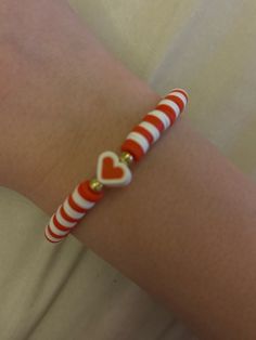 a red and white striped bracelet with heart charms on the end is attached to a woman's arm