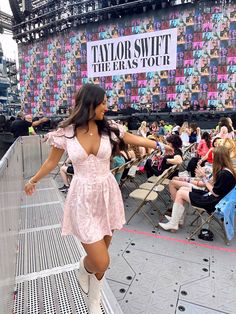 a woman in a pink dress and white boots is walking on the stage at a concert