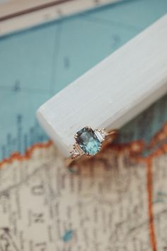 an engagement ring with a blue topaz sits on a map