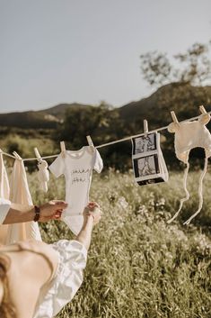 a woman is hanging clothes on a line with pictures and photos hung to dry in the sun