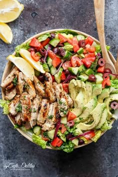 a salad with chicken, lettuce, tomatoes and olives in a bowl