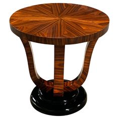 a wooden table sitting on top of a black base with an intricate design in the center