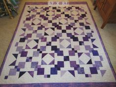 a purple and white quilt sitting on top of a floor