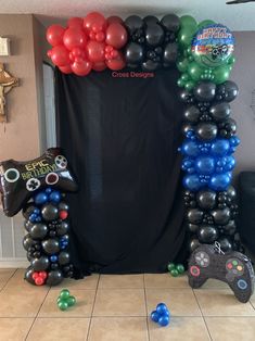 a bunch of balloons that are on the ground in front of a black curtain and some video game controllers