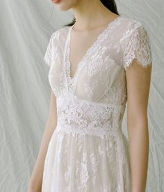 a woman wearing a white wedding dress standing in front of a white backdrop