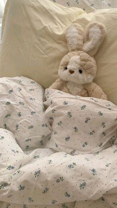 a stuffed animal sitting on top of a bed covered in white sheets and pillow cases