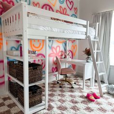 a white loft bed sitting next to a desk in a room with hearts painted on the wall