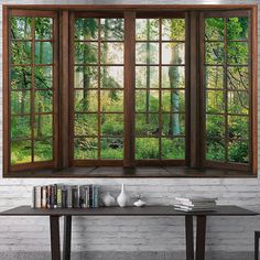 an open window with the view of a forest through it's wooden frame and glass panes