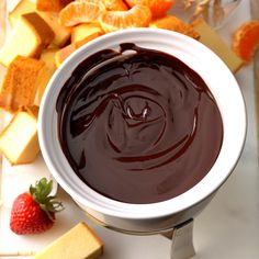 a white bowl filled with chocolate next to sliced oranges