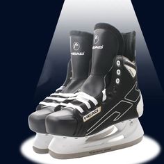 two pairs of ice skates with black and white boots on them, sitting in front of a spotlight