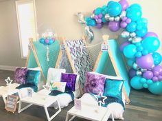 there are some chairs and tables in the room with blue, purple and white balloons