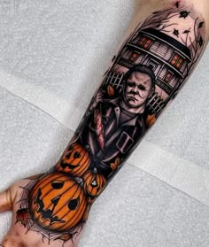 a man's arm with a halloween scene on it and pumpkins in the foreground