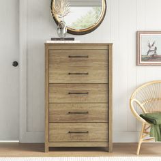 a wooden dresser sitting in front of a mirror on top of a white wall next to a wicker chair