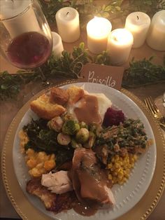 a white plate topped with lots of food next to candles and wine glasses on top of a table