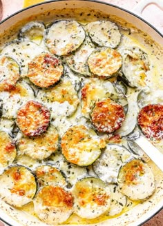 a pan filled with cooked zucchini and cheese on top of a table next to some bread