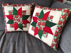 two red and green christmas themed pillows on a gray couch next to a bookcase