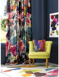 a chair sitting next to a window covered in colorful curtains