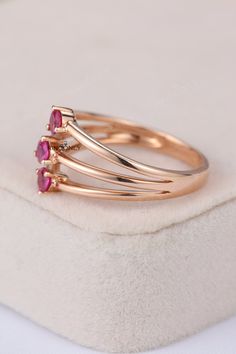 three stone ring set in rose gold with pink stones on the sides and white background