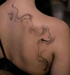 the back of a woman's shoulder with an abstract tattoo design on her left side