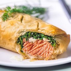 a meat and spinach filled pastry on a white plate with a fork next to it