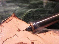 a fountain pen sitting on top of a piece of wood with an intricate carving pattern