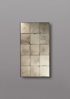 a square mirror mounted to the side of a wall with multiple tiles on it's surface