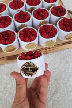 a hand holding a small white box filled with red roses