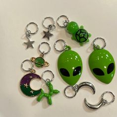 a collection of alien keychains are shown on a white surface with stars and moon charms