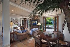 a living room filled with lots of furniture and a large tree in the middle of it