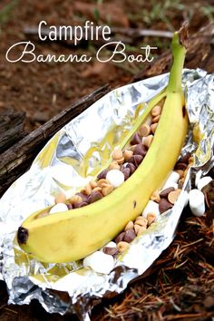 a banana sitting on top of tin foil covered in nuts and beans with the words campfire banana boat written above it