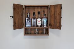 an open wooden cabinet with liquor bottles in it