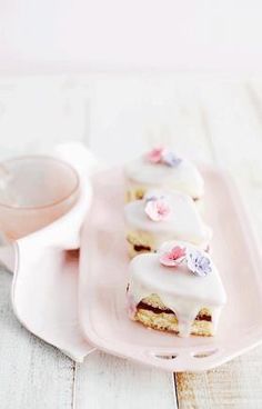 there is a pink plate with some cake on it and a cup next to it