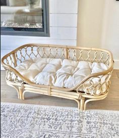 a wicker dog bed is on the floor in front of a fireplace and rug