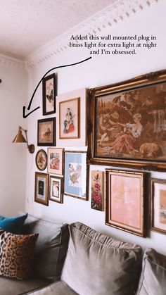 a living room filled with lots of framed pictures on the wall above a gray couch