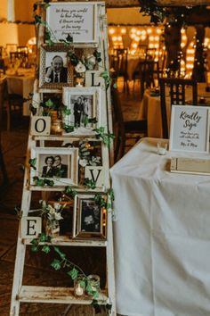 an old ladder is decorated with photos and greenery for a wedding reception at night