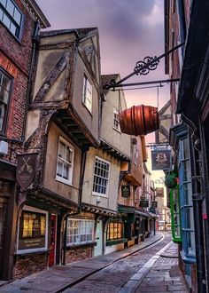 an alleyway with old buildings and shops on both sides in the city center at sunset