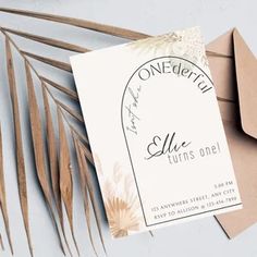 a close up of an envelope with a card on it next to some palm leaves