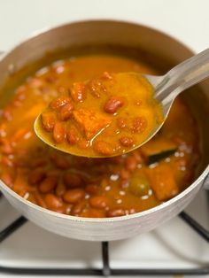 a spoon full of beans and carrots on top of a stove