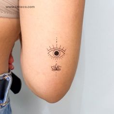 a woman's leg with an eye tattoo on her left side, and a flower in the middle