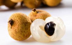 two pieces of fruit sitting next to each other on a white surface with oranges in the background