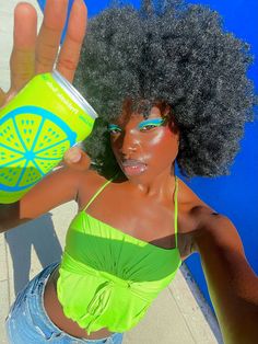 a woman with an afro holding up a can of soda