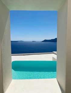 an outdoor swimming pool with blue water and white walls, overlooking the ocean in greece