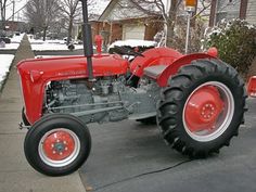 an old red tractor parked in front of a house