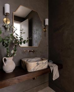 a bathroom sink sitting under a mirror next to a vase with a plant in it