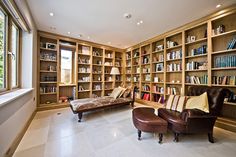 a room with many bookshelves and leather chairs in front of the couches