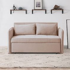 a beige couch sitting on top of a rug in a living room next to a white wall