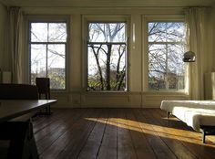 an empty room with three windows and wooden floors