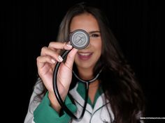 a woman holding a stethoscope in her right hand and smiling at the camera