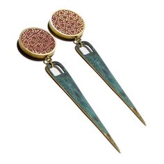 two pairs of gold and green earrings with pink dots on the top, one is dangling from